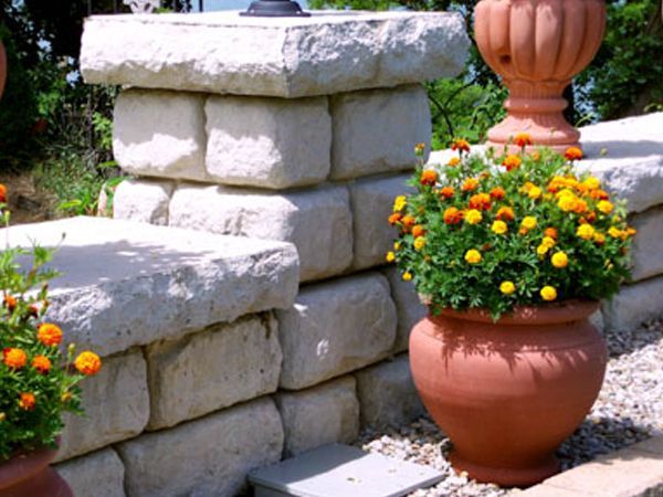 A brick wall with a pot of flowers in front of it