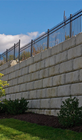 A large concrete wall with a metal fence surrounding it.