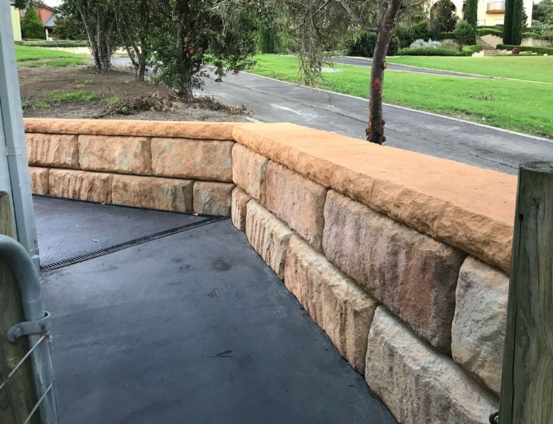 A stone wall is sitting next to a road in a park.