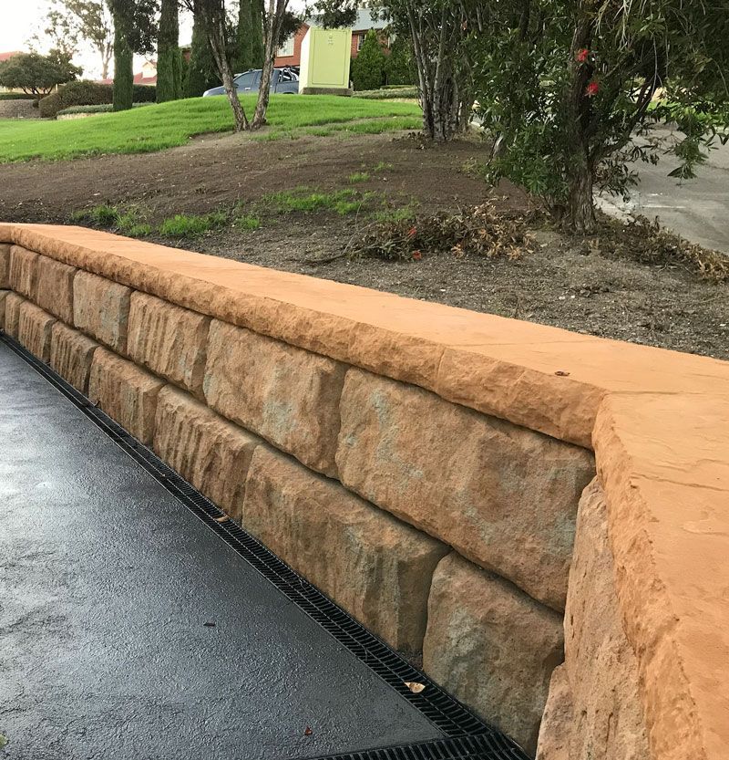 A stone wall in a park with trees in the background.
