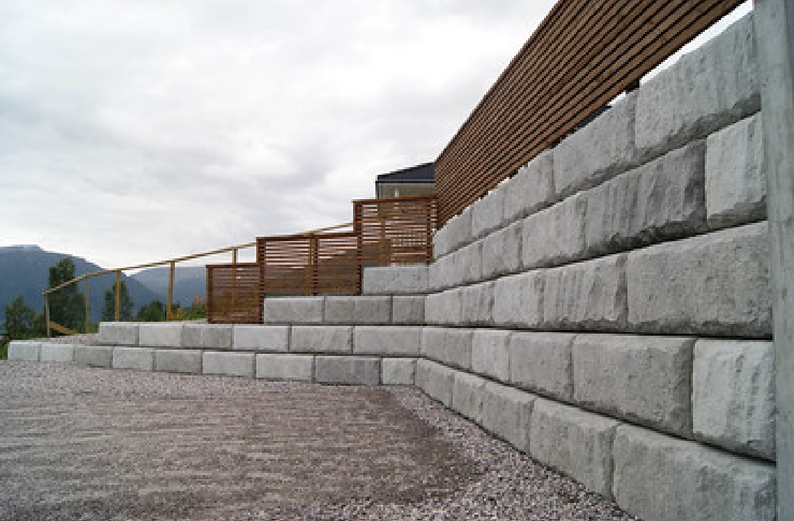 A large concrete wall with a wooden fence in the background.