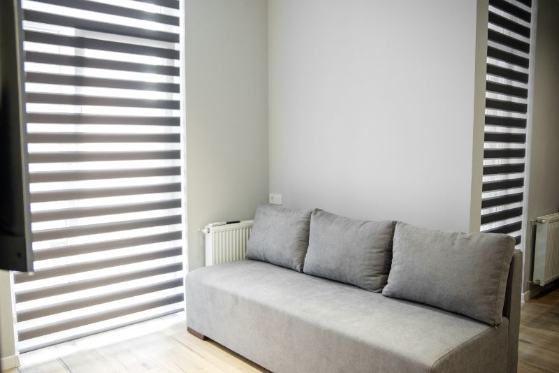 a living room with a couch and striped blinds Dual shades next to a cozy gray couch enhancing ambiance and mood Georgia