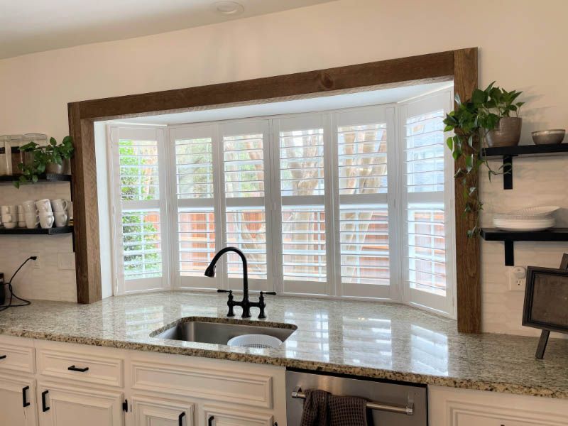 a kitchen with a sink and a large window with shutters custom shutters Georgia.