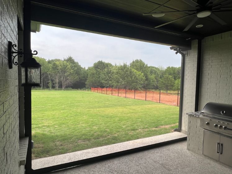 A back yard is seen through a translucent patio shade. 