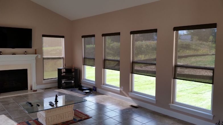 A living room with lots of windows and a fireplace, with cordless window shades.