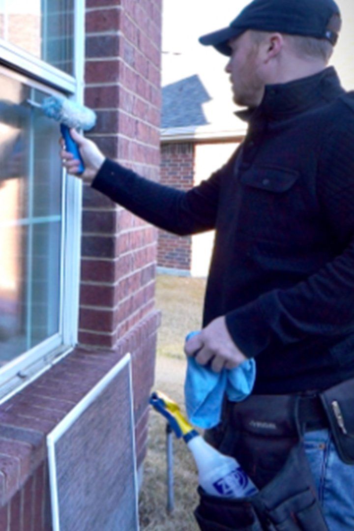 a man is cleaning a window with a blue cloth quarterly window washing services Love is Blinds