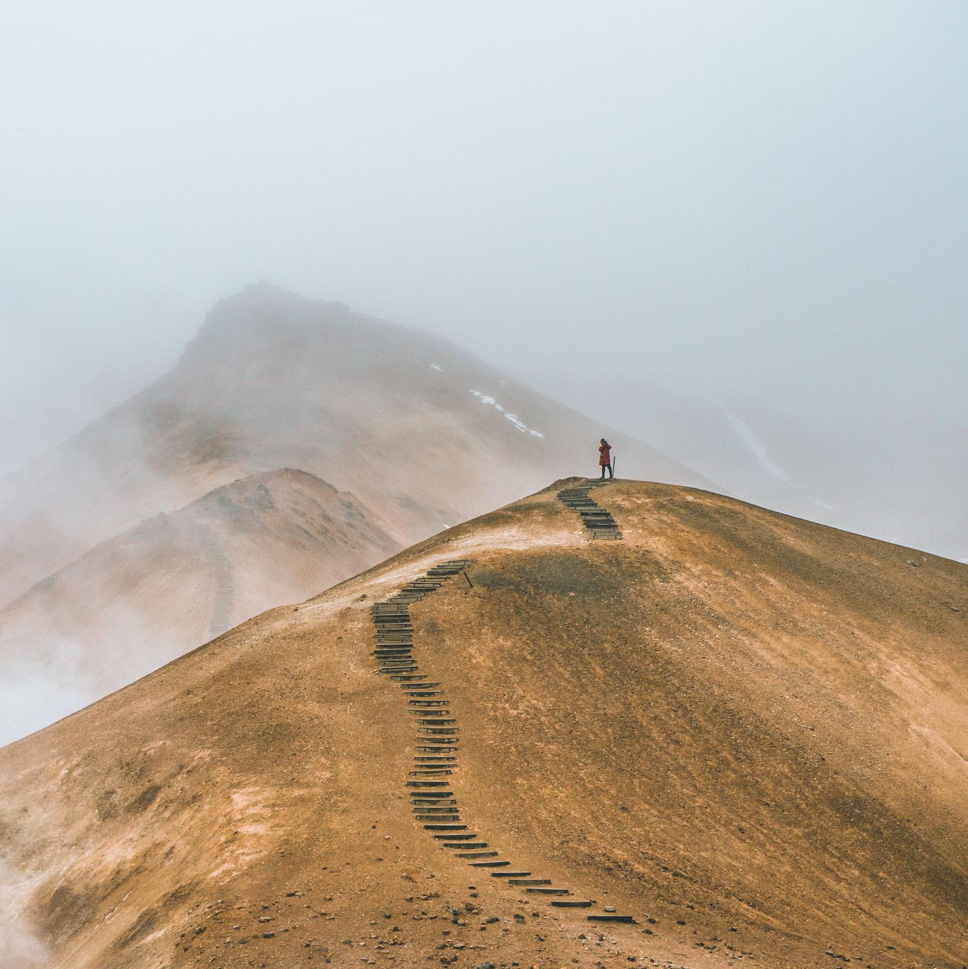 Traveler walking a path of stairs across sandy mountain peaks