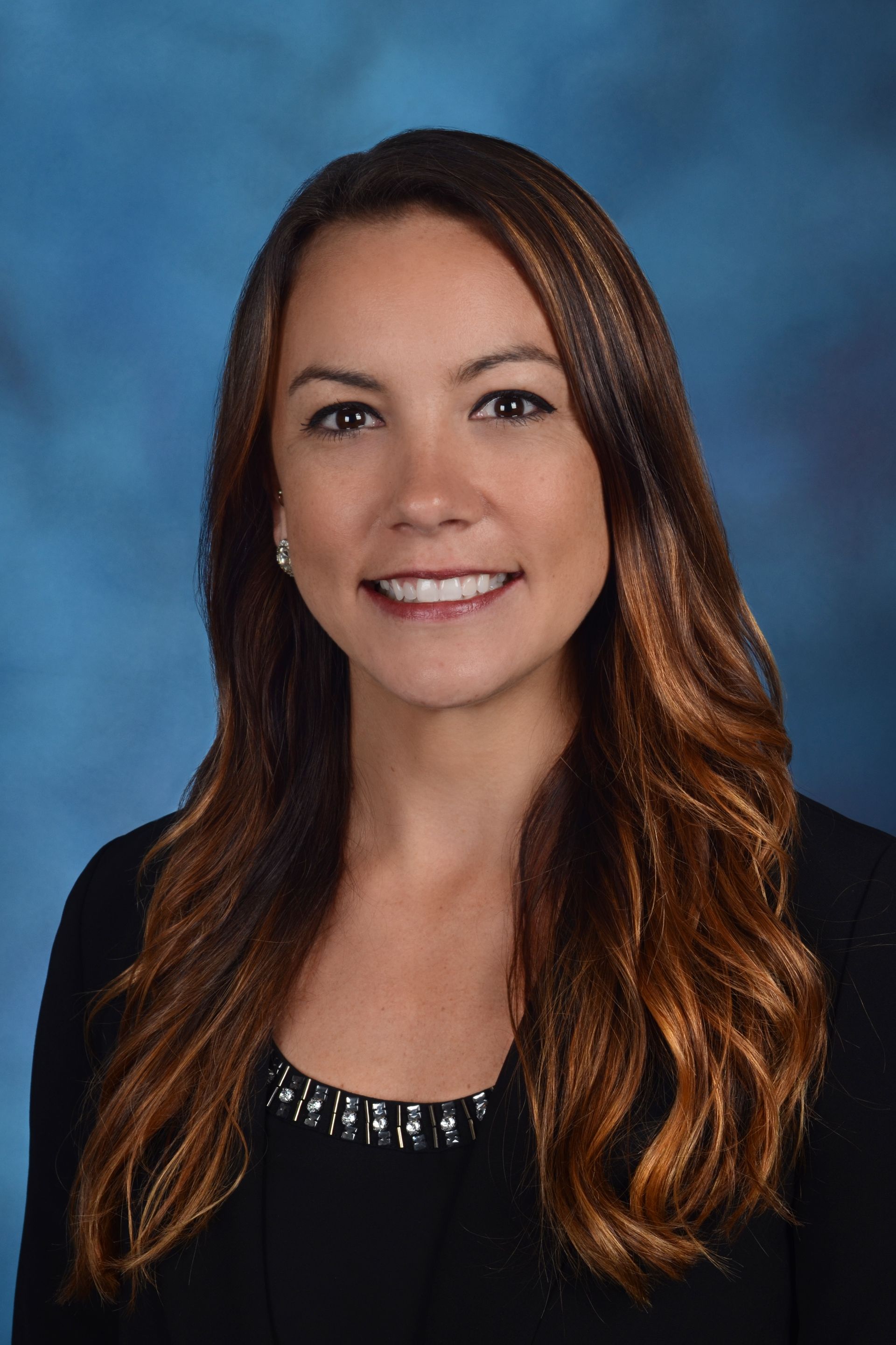 A woman is smiling in front of a blue background with the letter r on it