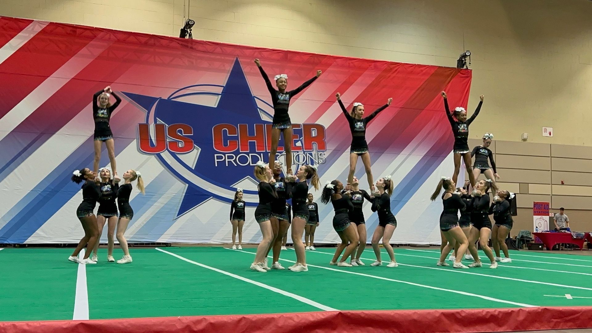 A group of cheerleaders are performing in front of a premier athletics logo