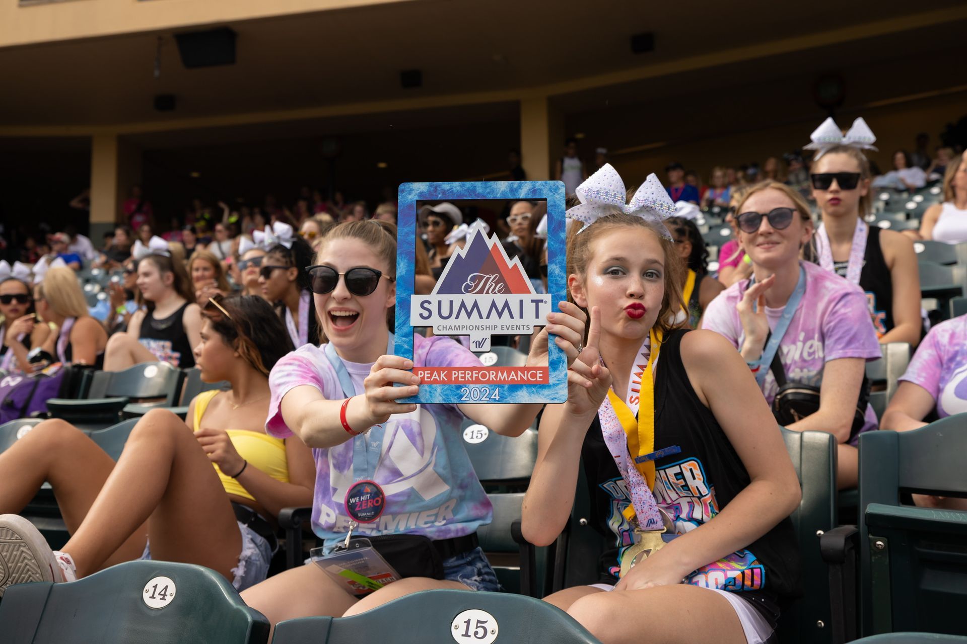 A group of cheerleaders are performing in front of a premier athletics logo