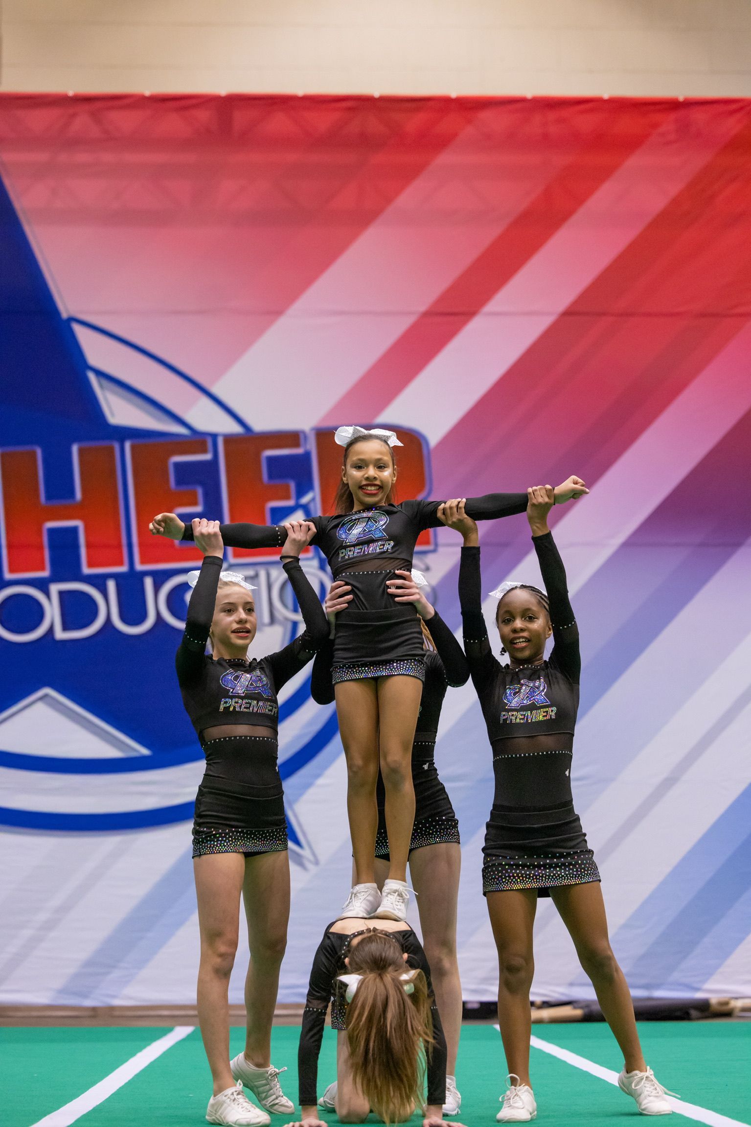 A group of cheerleaders are performing a trick on a stage.