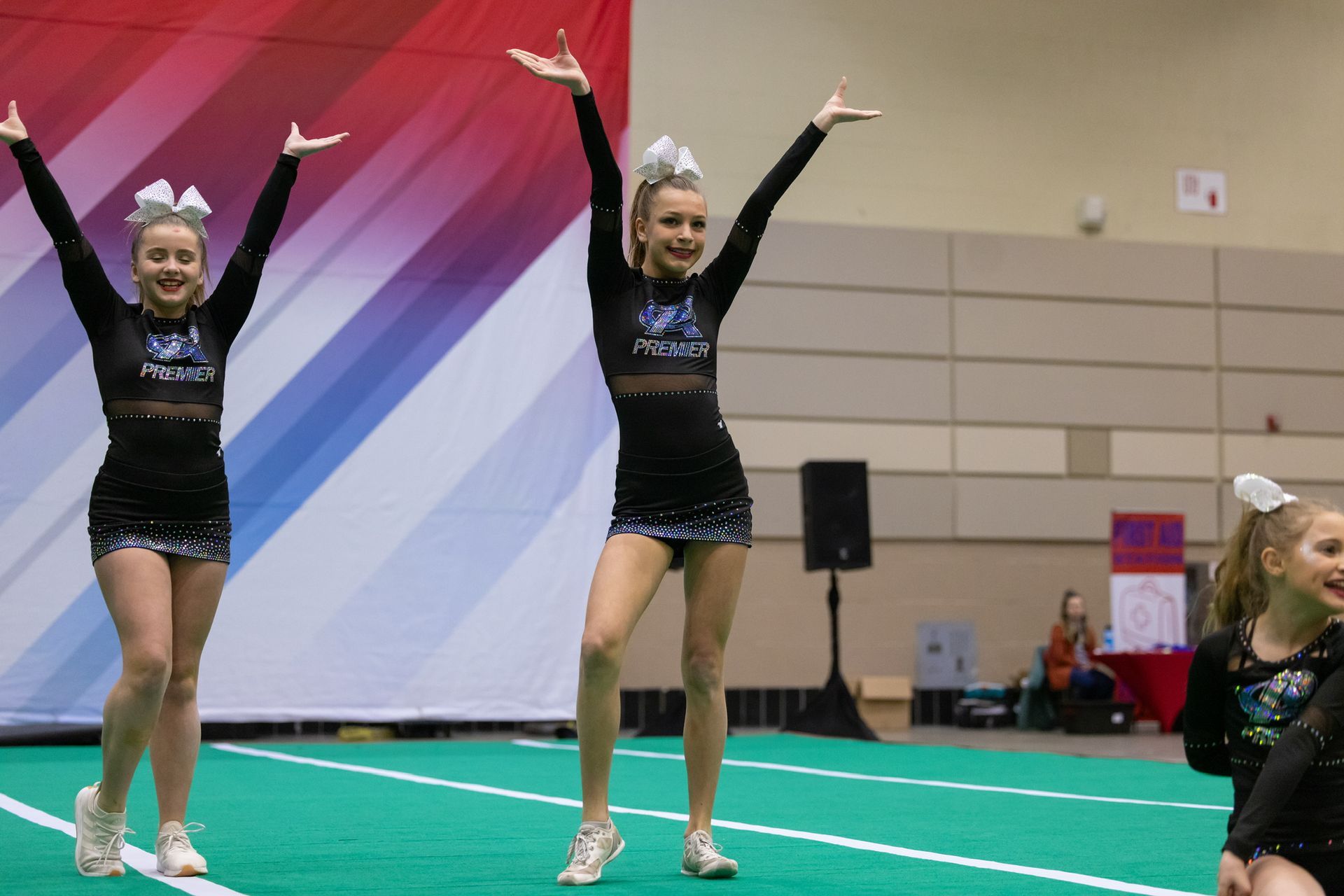 A young girl in a cheerleading outfit is standing in front of a wall with balloons.