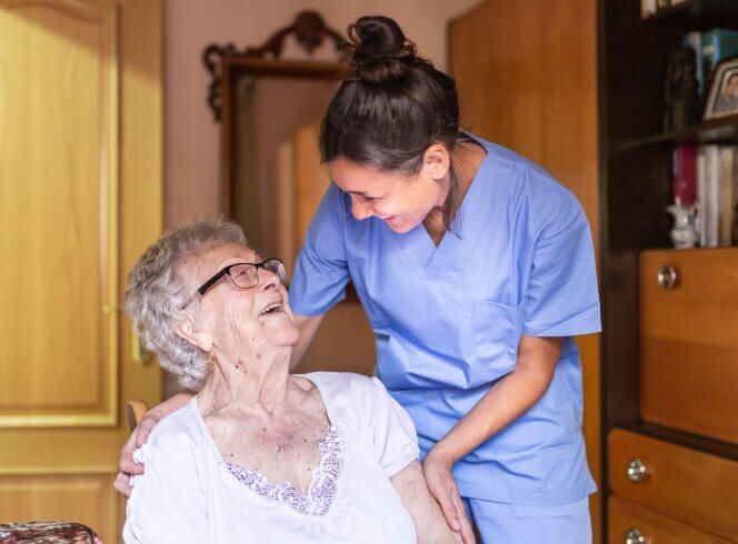 A nurse is talking to an elderly woman in a chair.