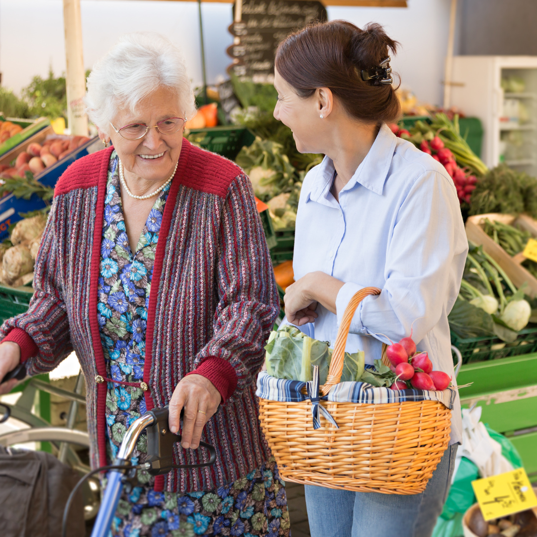 Two women are standing next to each other and one is holding a basket of vegetables