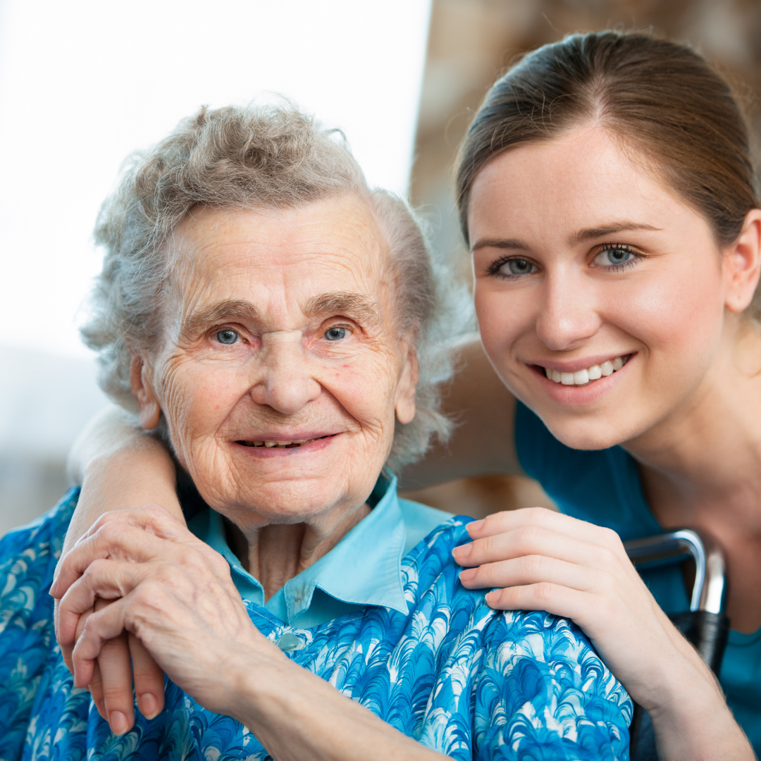 A young woman is hugging an older woman in a wheelchair.