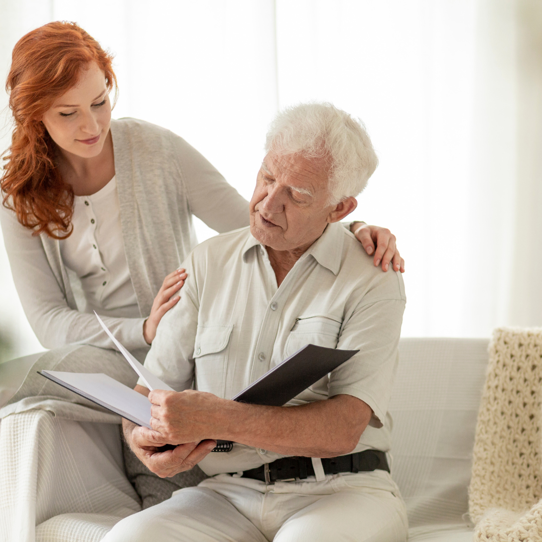 A woman is sitting next to an older man who is reading a book