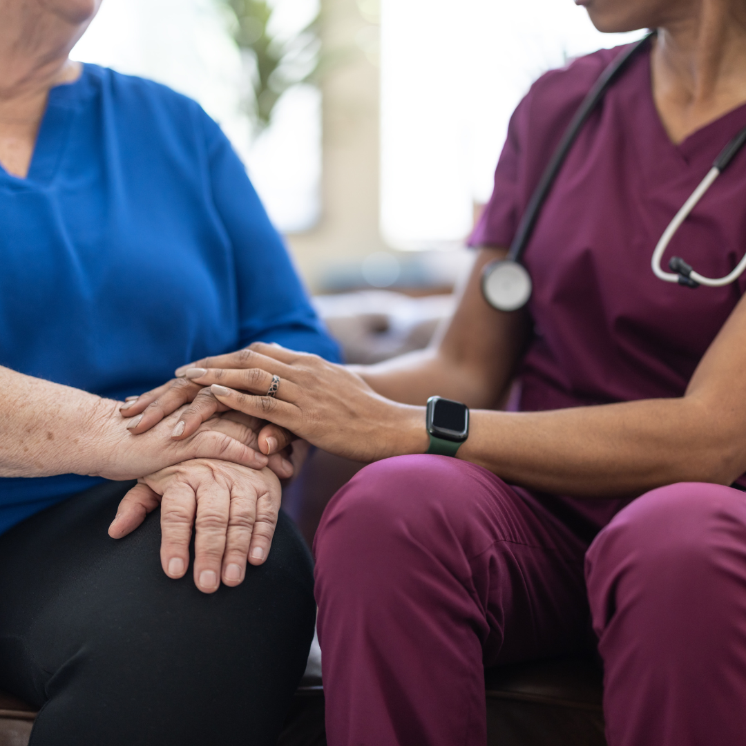 A nurse is holding the hands of an elderly woman