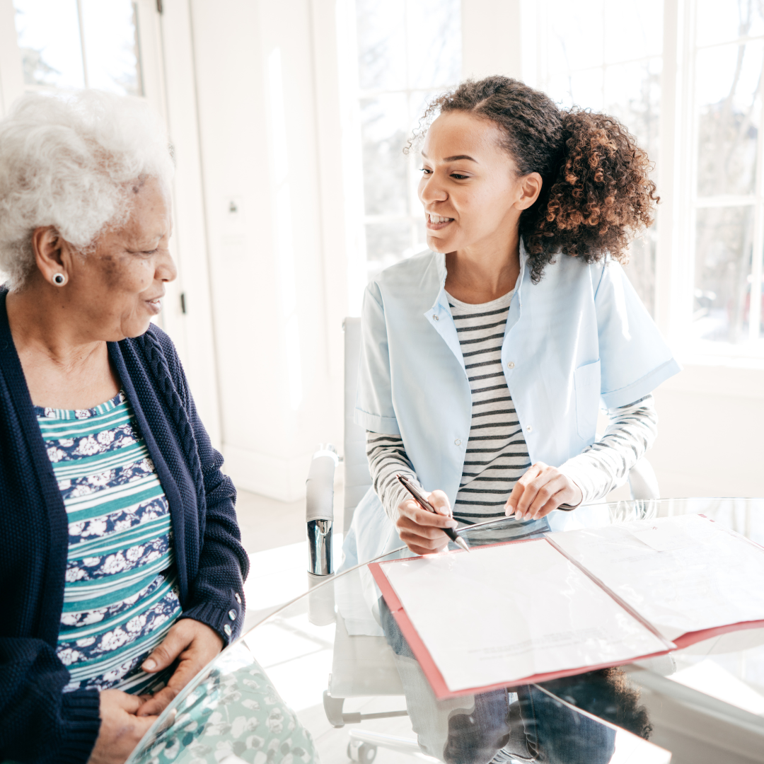 A woman is sitting at a table talking to an older woman.