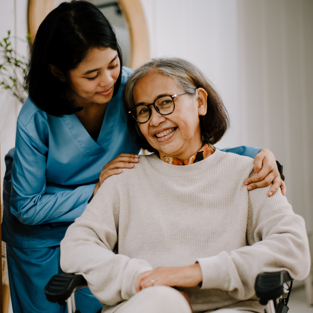 A woman is hugging an older woman in a wheelchair.