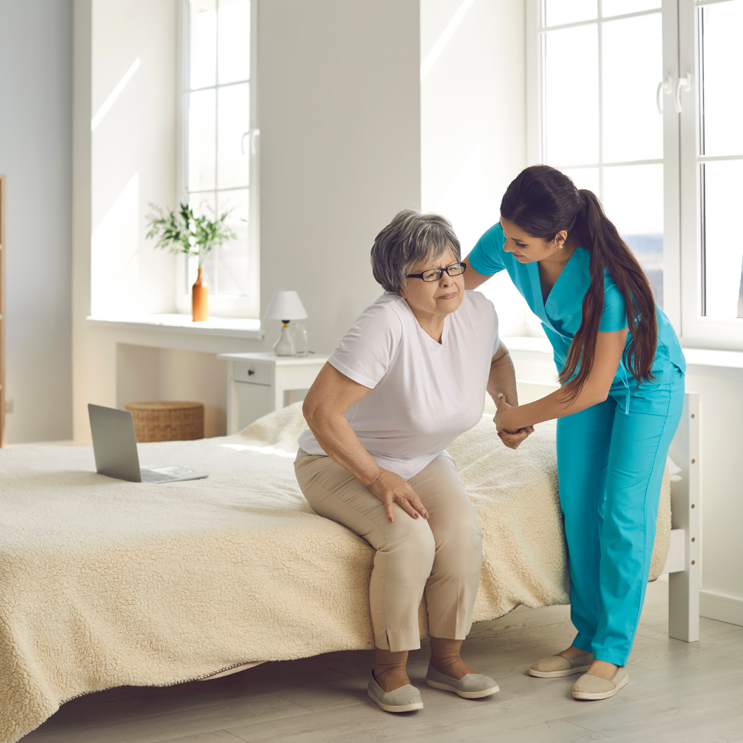 A nurse is helping an elderly woman sit on a bed.