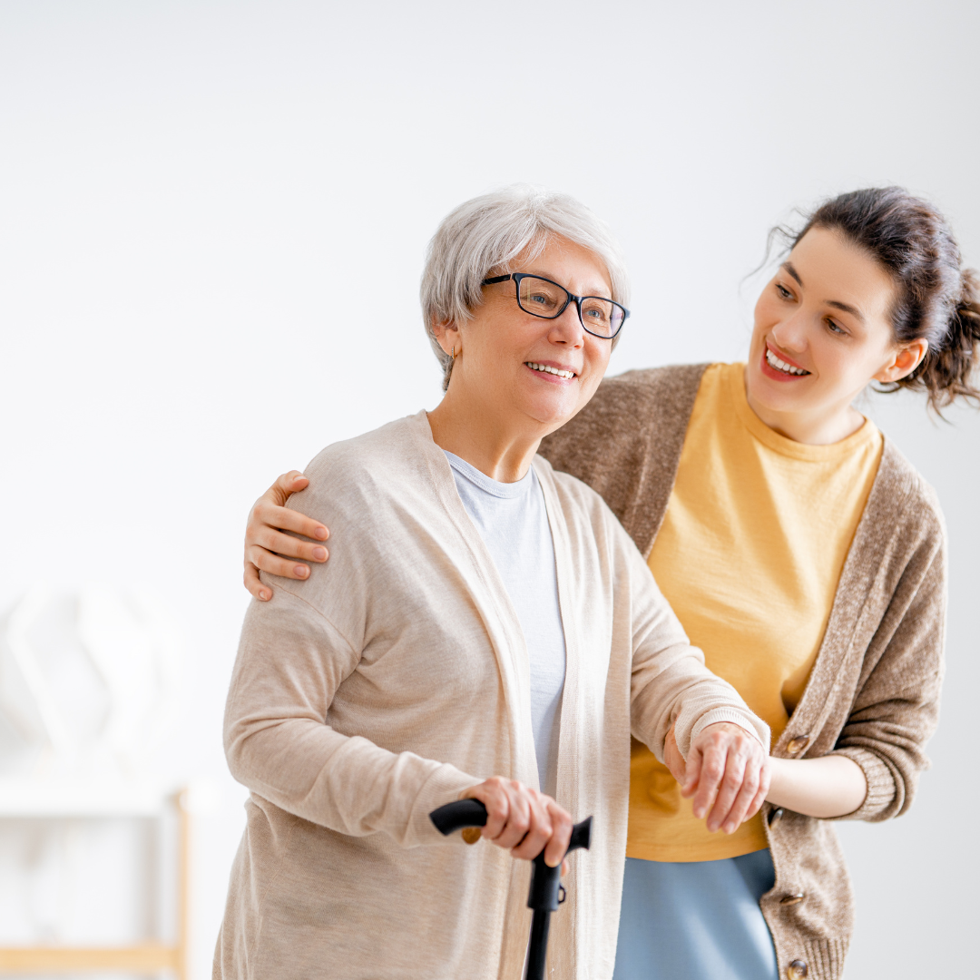 A young woman is helping an older woman with a cane.