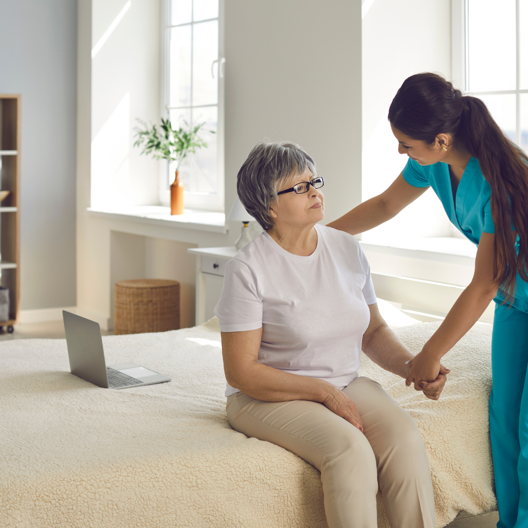 A nurse is helping an elderly woman sit on a bed