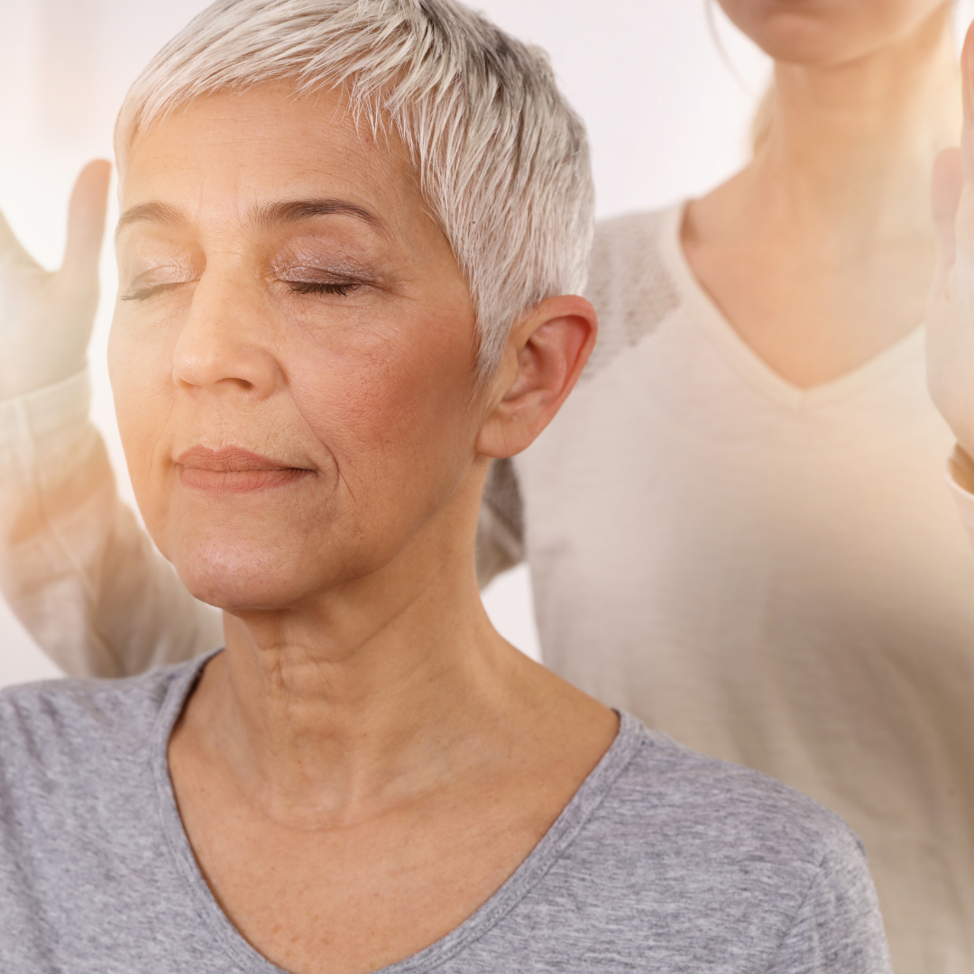 A woman with short white hair is meditating with her eyes closed.