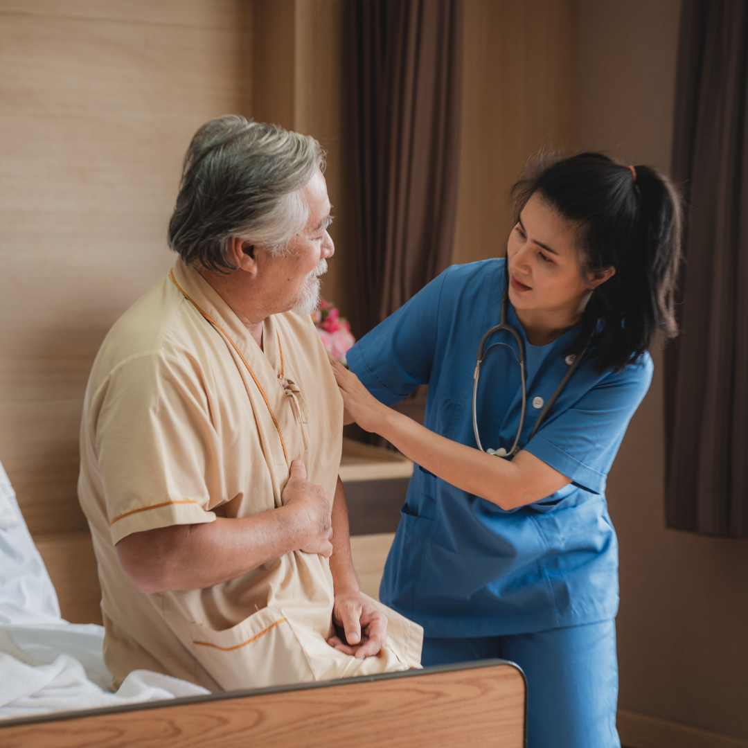 A nurse is talking to an elderly man in a hospital bed.