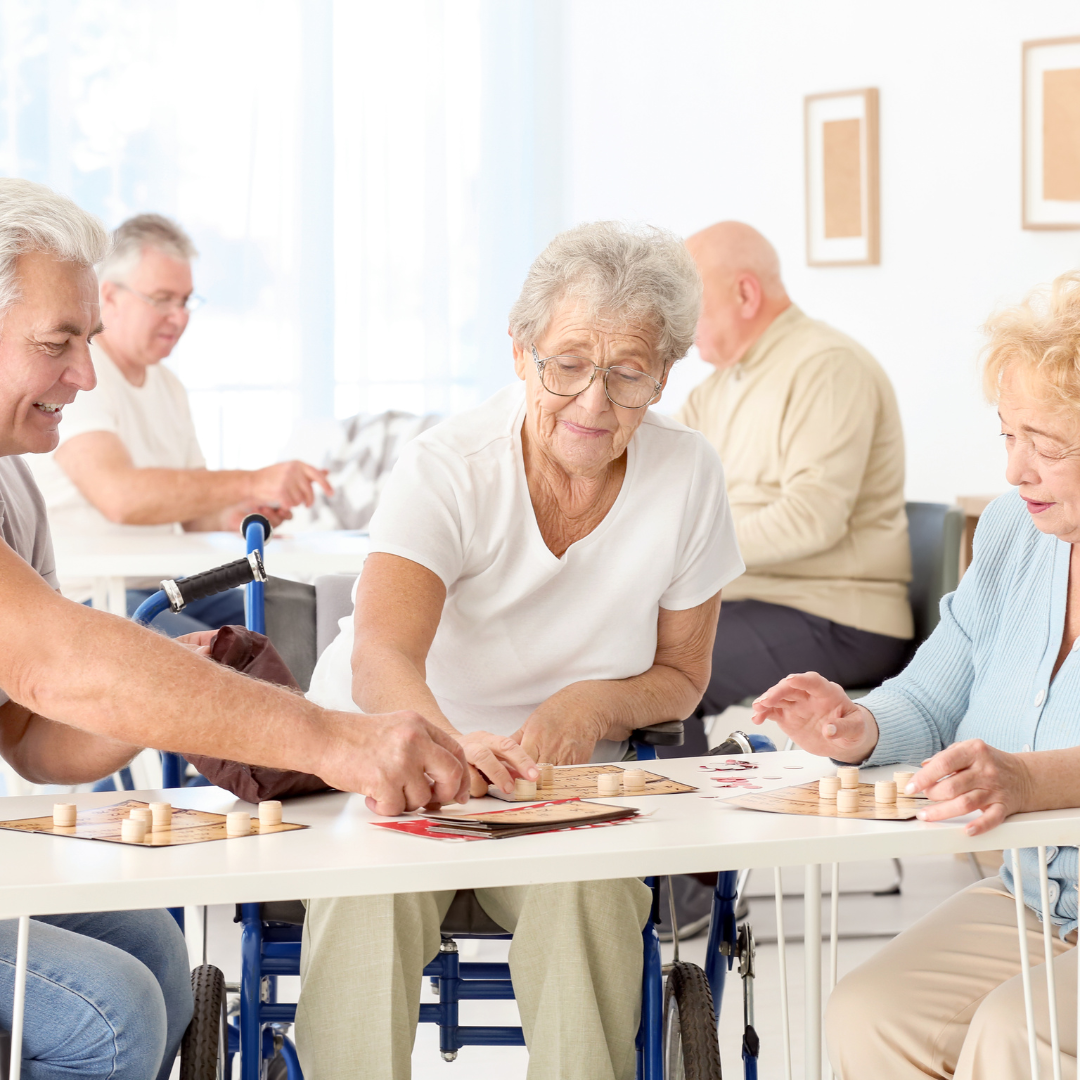 A group of elderly people are sitting around a table playing a game of chess.