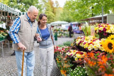 An elderly couple is shopping for flowers at a market.