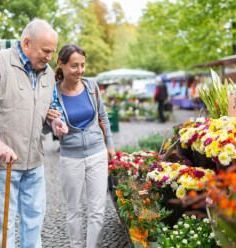 A man and a woman are looking at flowers at a market.