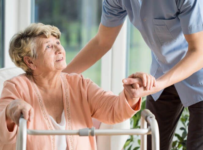 A man is helping an elderly woman with a walker.