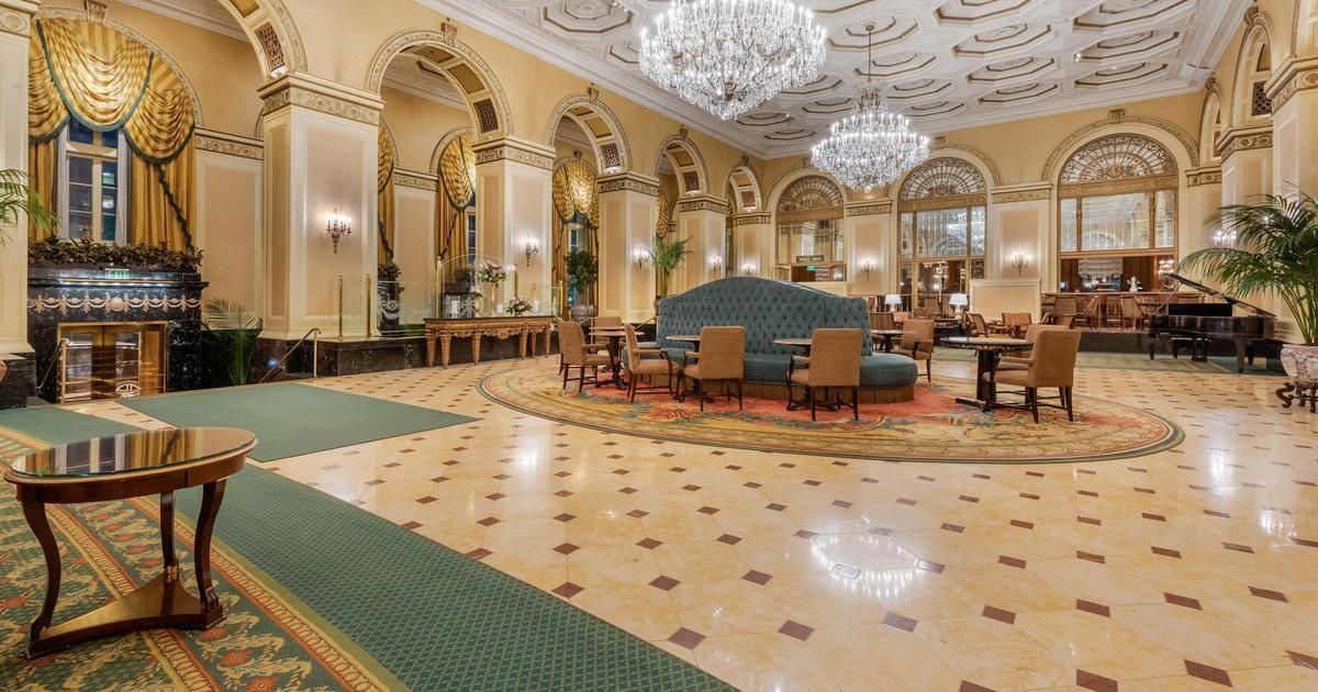 A large lobby with a couch , chairs , tables and a chandelier.