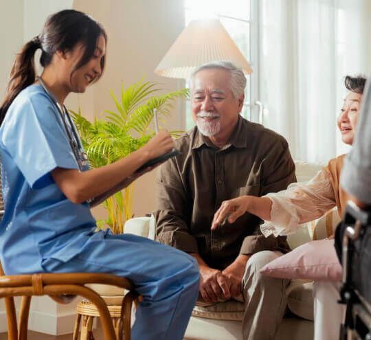 A nurse is sitting on a stool talking to a group of people.