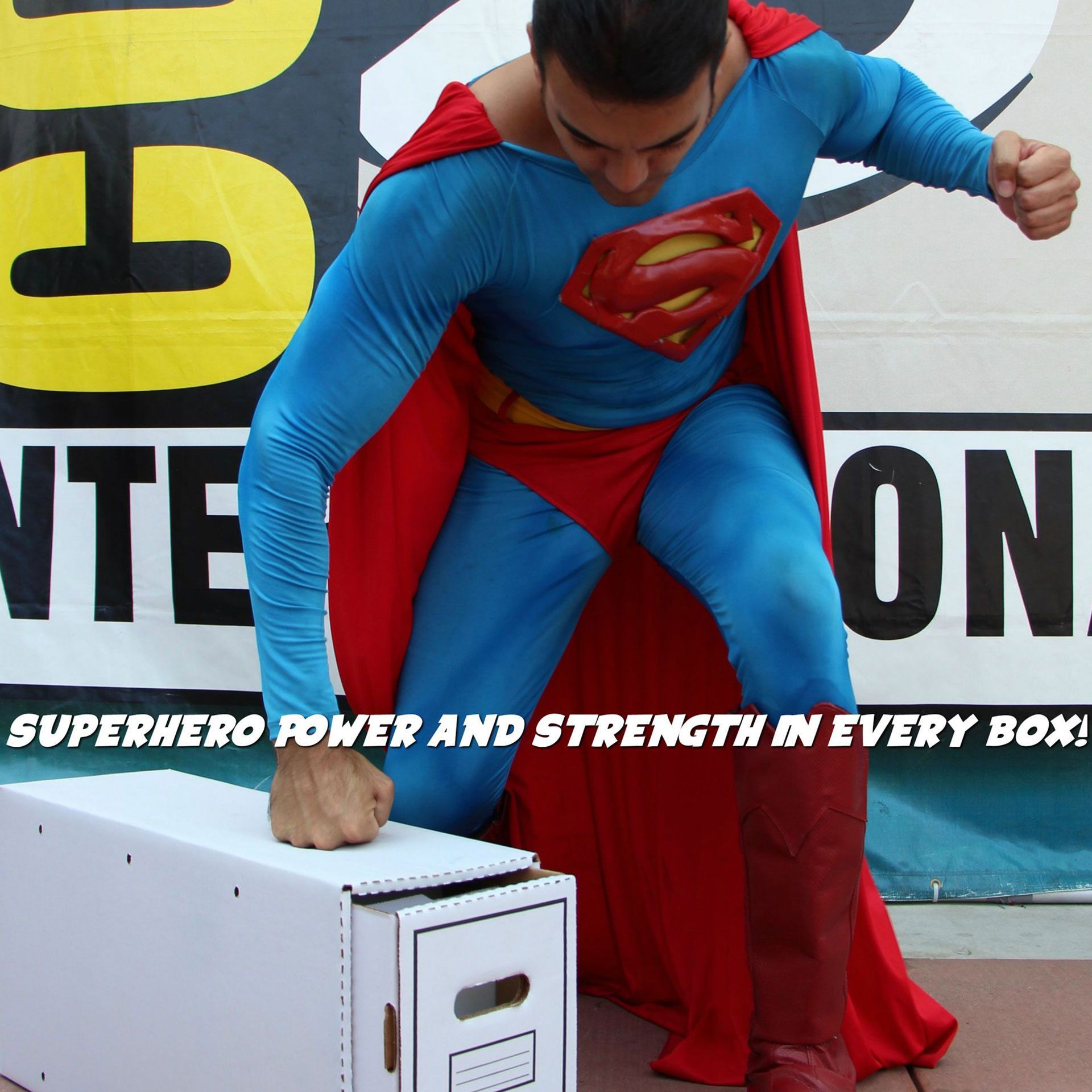 A man in a superman costume stands in front of a sign that says superhero power and strength in every box