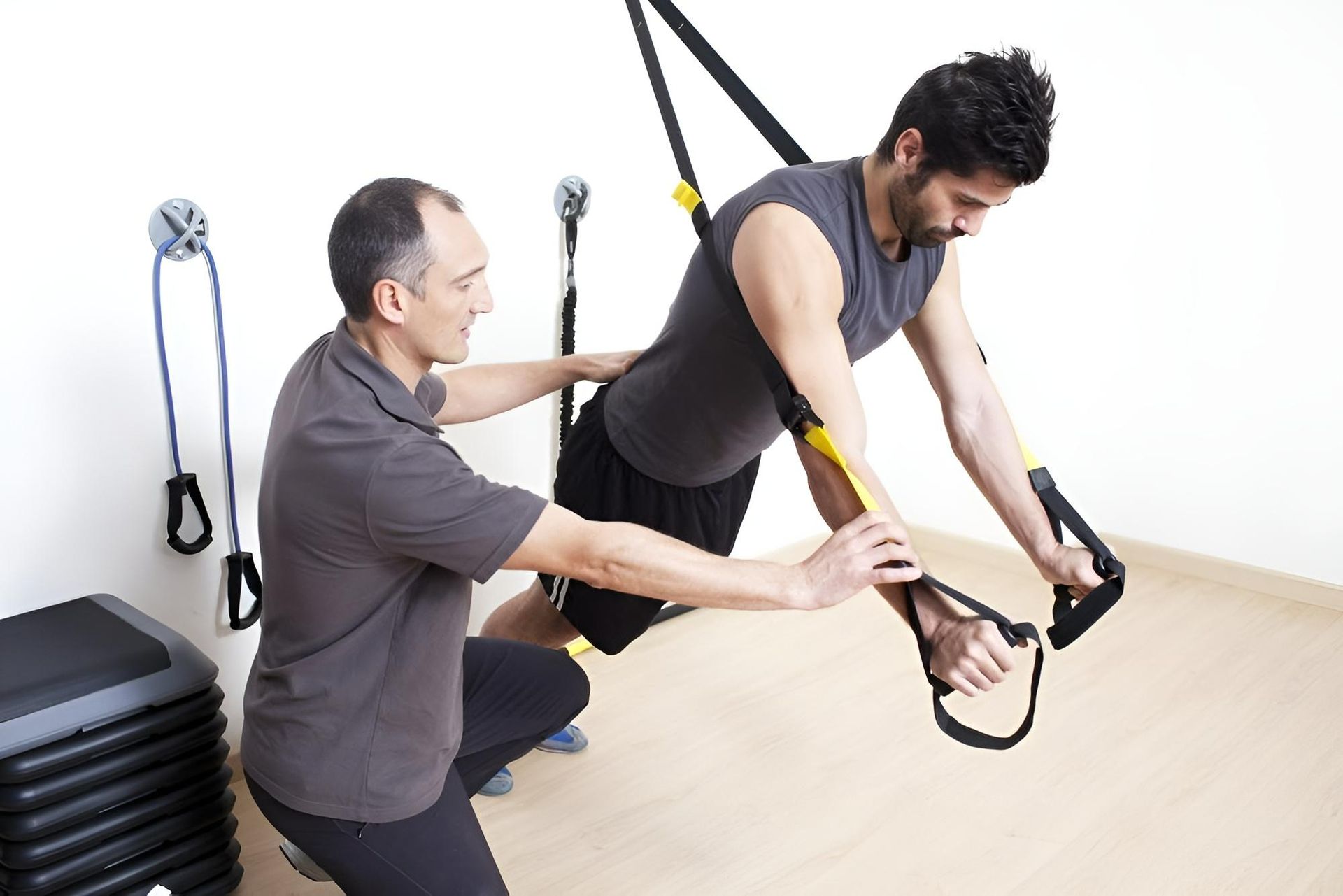 A Man Is Helping Another Man Do Exercises — Action Physiotherapy in Cooks Hill, NSW