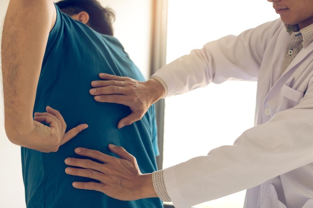 A Doctor Is Examining a Patient's Back — Action Physiotherapy in Cooks Hill, NSW