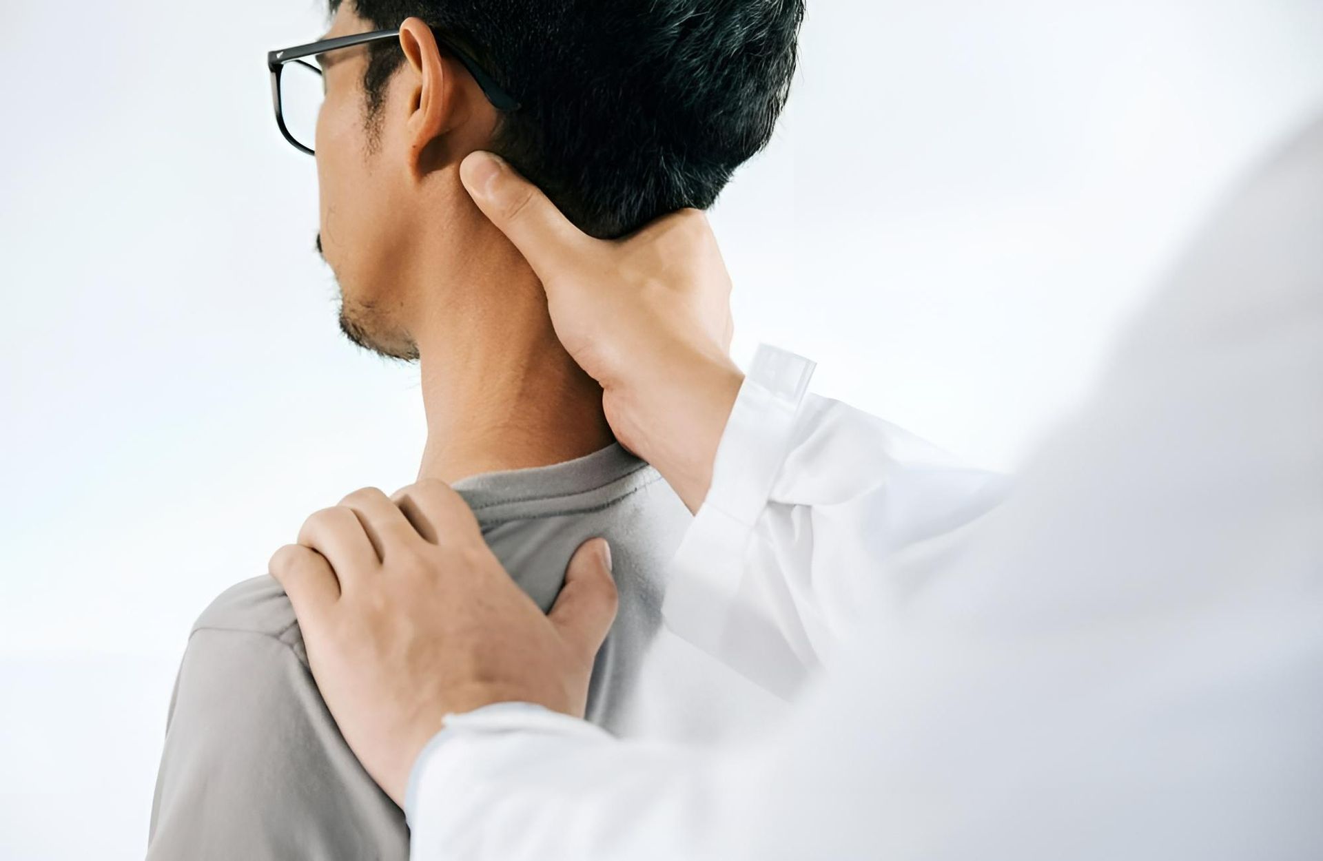 A Doctor Is Examining a Man's Neck and Shoulder — Action Physiotherapy in Cooks Hill, NSW