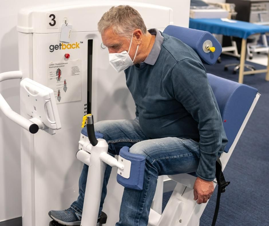 A Man Wearing a Mask Is Sitting on A Machine — Action Physiotherapy in Cooks Hill, NSW
