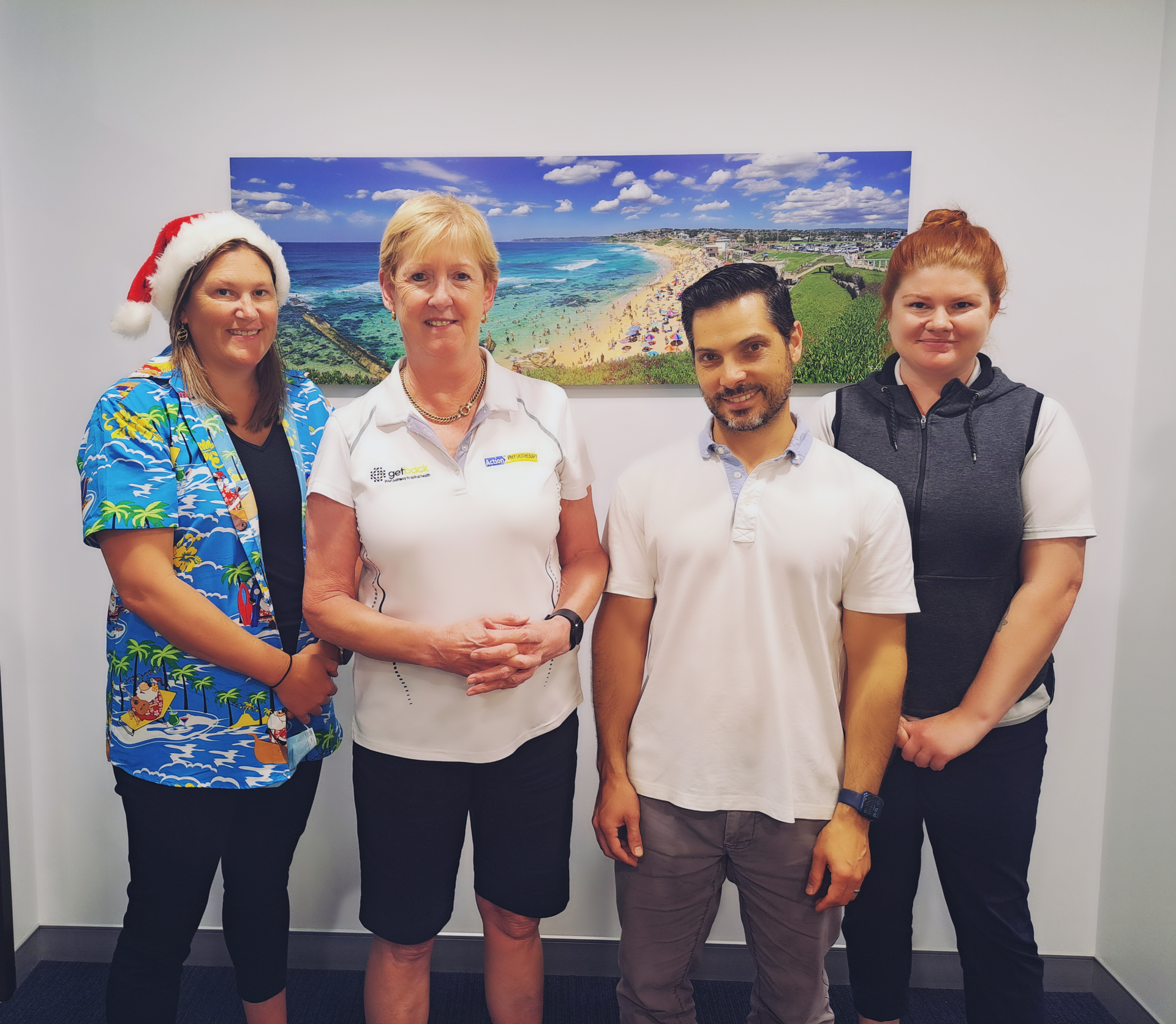 A Group of People Posing for A Picture with One Wearing a Santa Hat — Action Physiotherapy in Cooks Hill, NSW