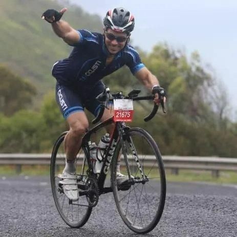 A Man Is Riding a Bicycle with A Number 21675 on The Handlebars — Action Physiotherapy in Cooks Hill, NSW
