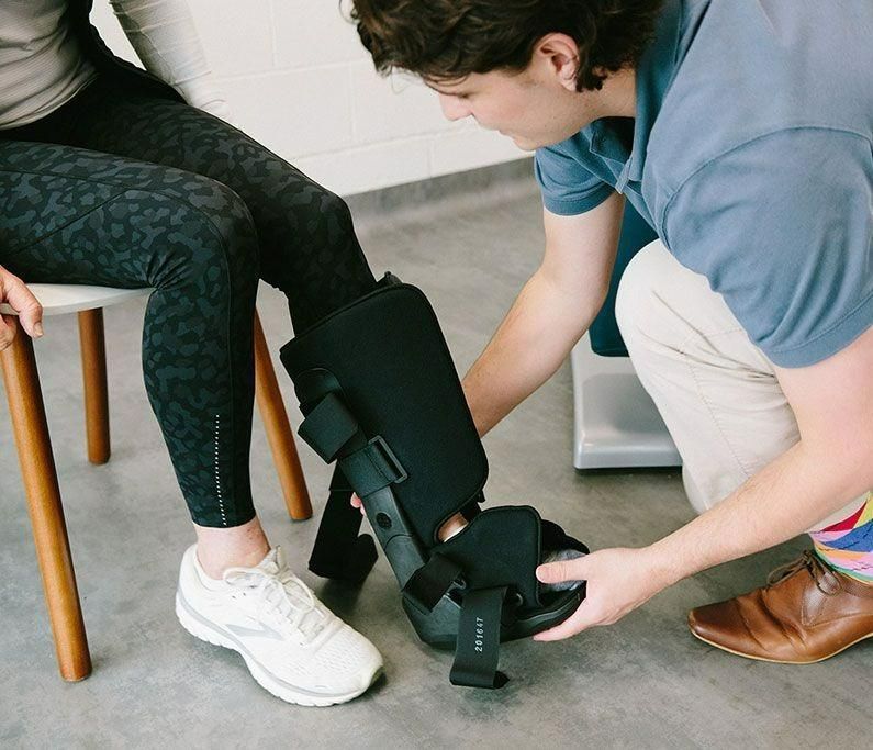 A Man Is Putting a Boot on A Woman's Foot — Action Physiotherapy in Cooks Hill, NSW
