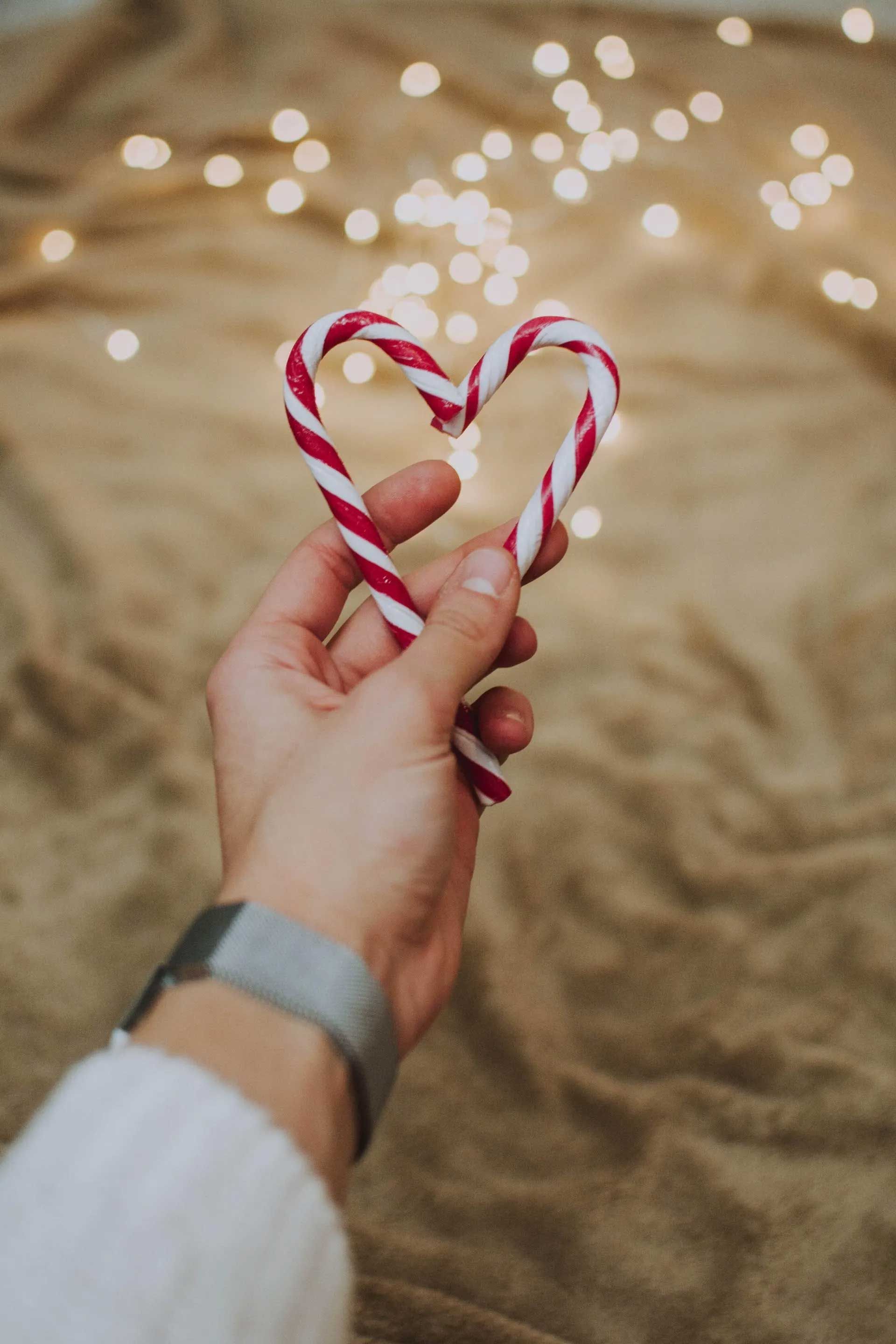 A Person Is Holding a Heart Shaped Candy Cane in Their Hand — Action Physiotherapy in Cooks Hill, NSW