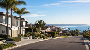 A two-story suburban house with a tan exterior, gray siding accents, a two-car garage, and a xeriscaped front yard.