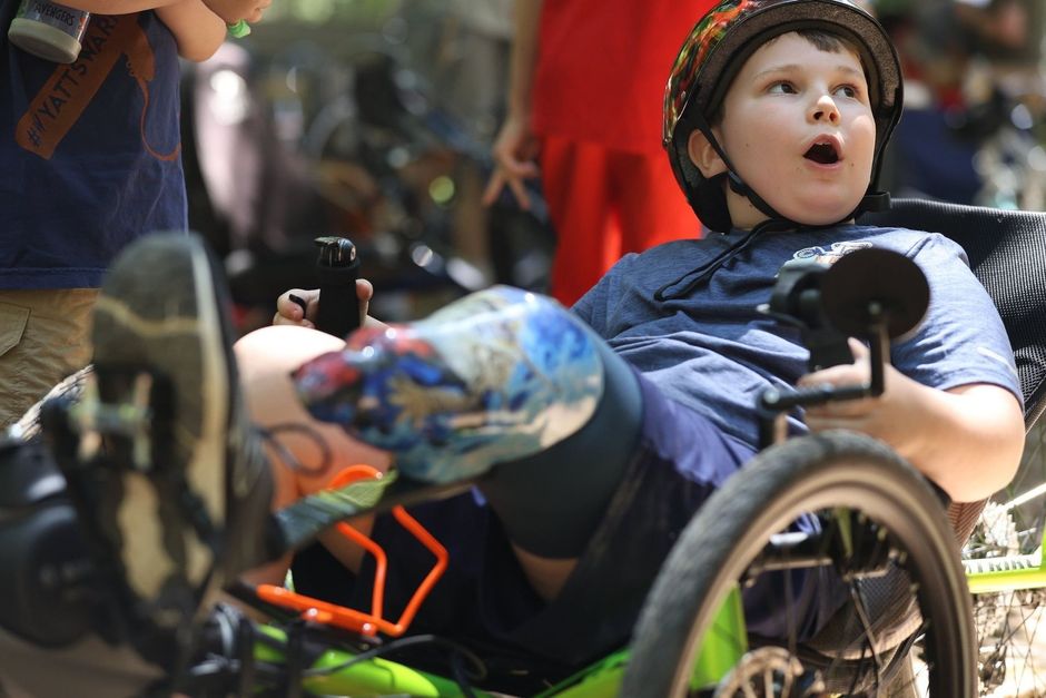 A young boy in a wheelchair is wearing a helmet.
