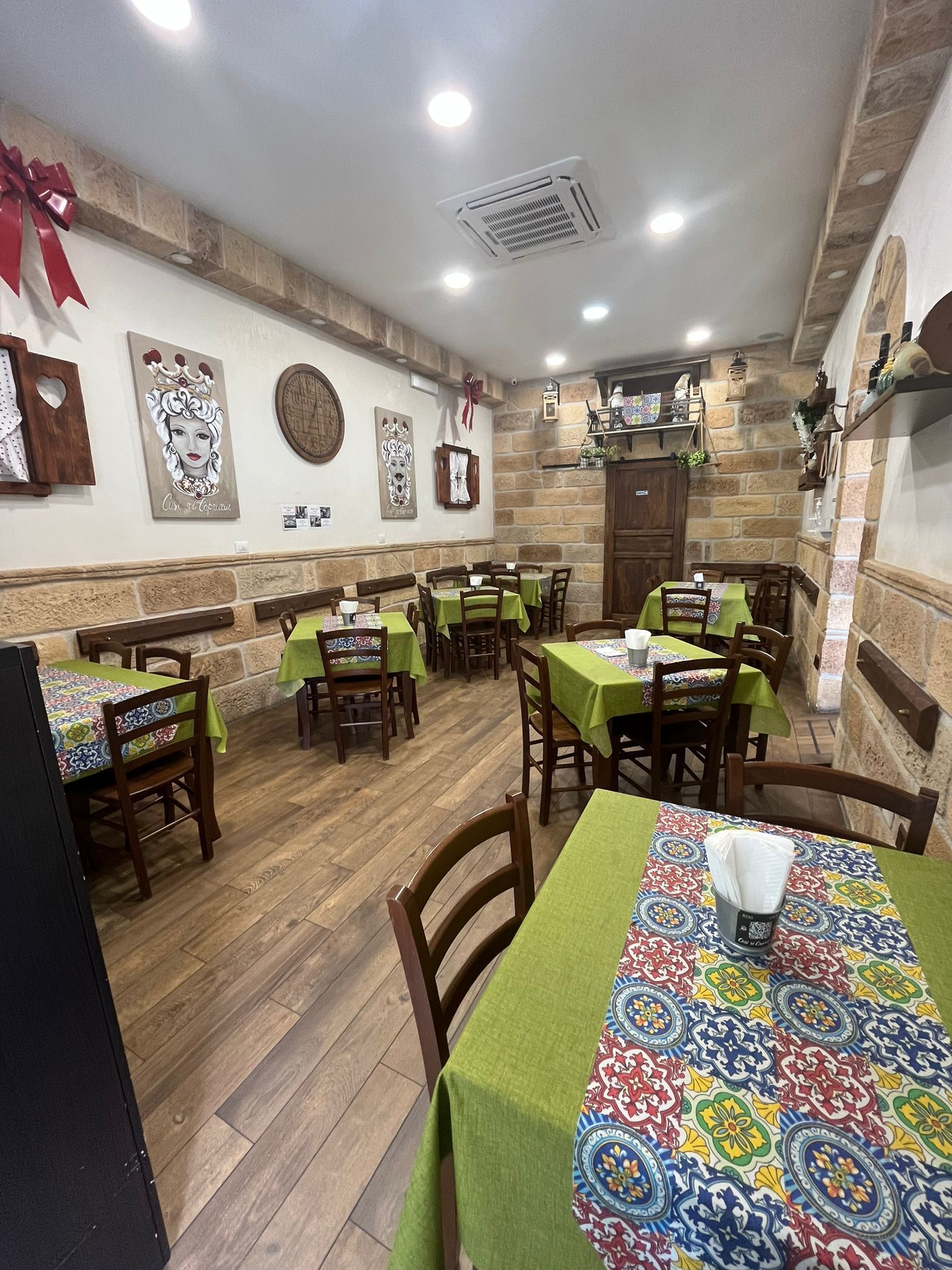 Un ristorante con tavoli, sedie e una tovaglia verde.