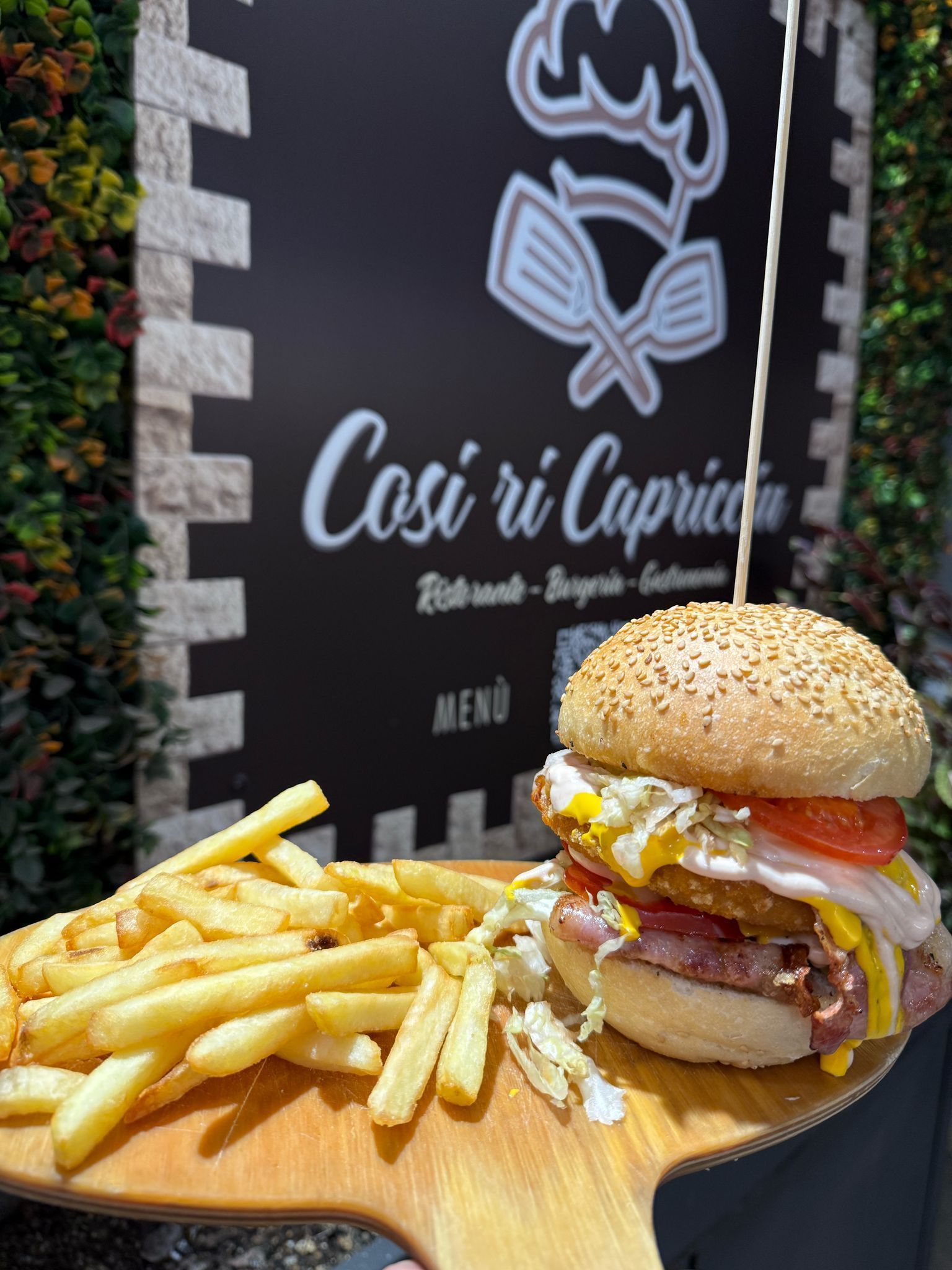 Un hamburger e patatine fritte su un tagliere di legno.