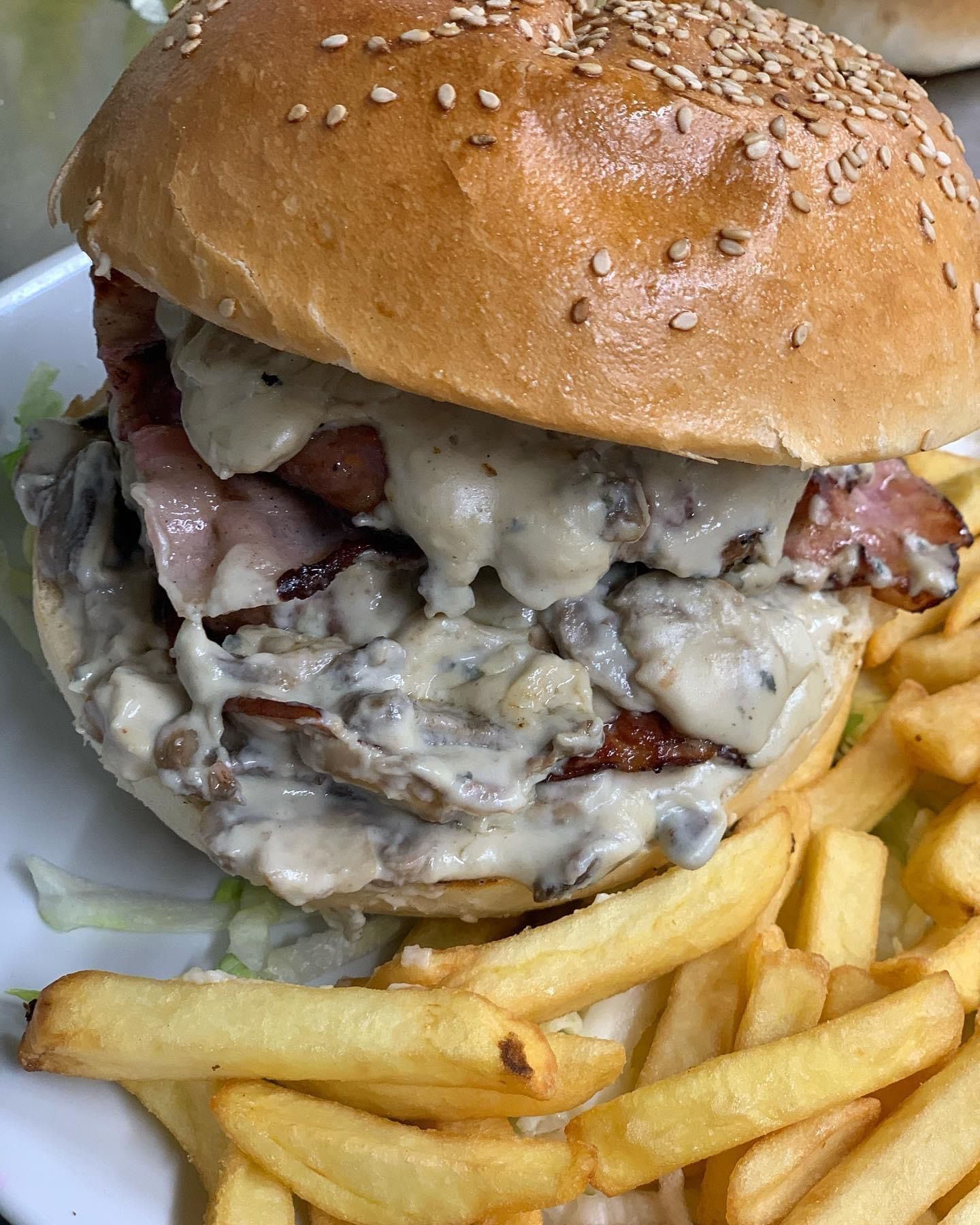 Un primo piano di un hamburger e patatine fritte su un piatto.