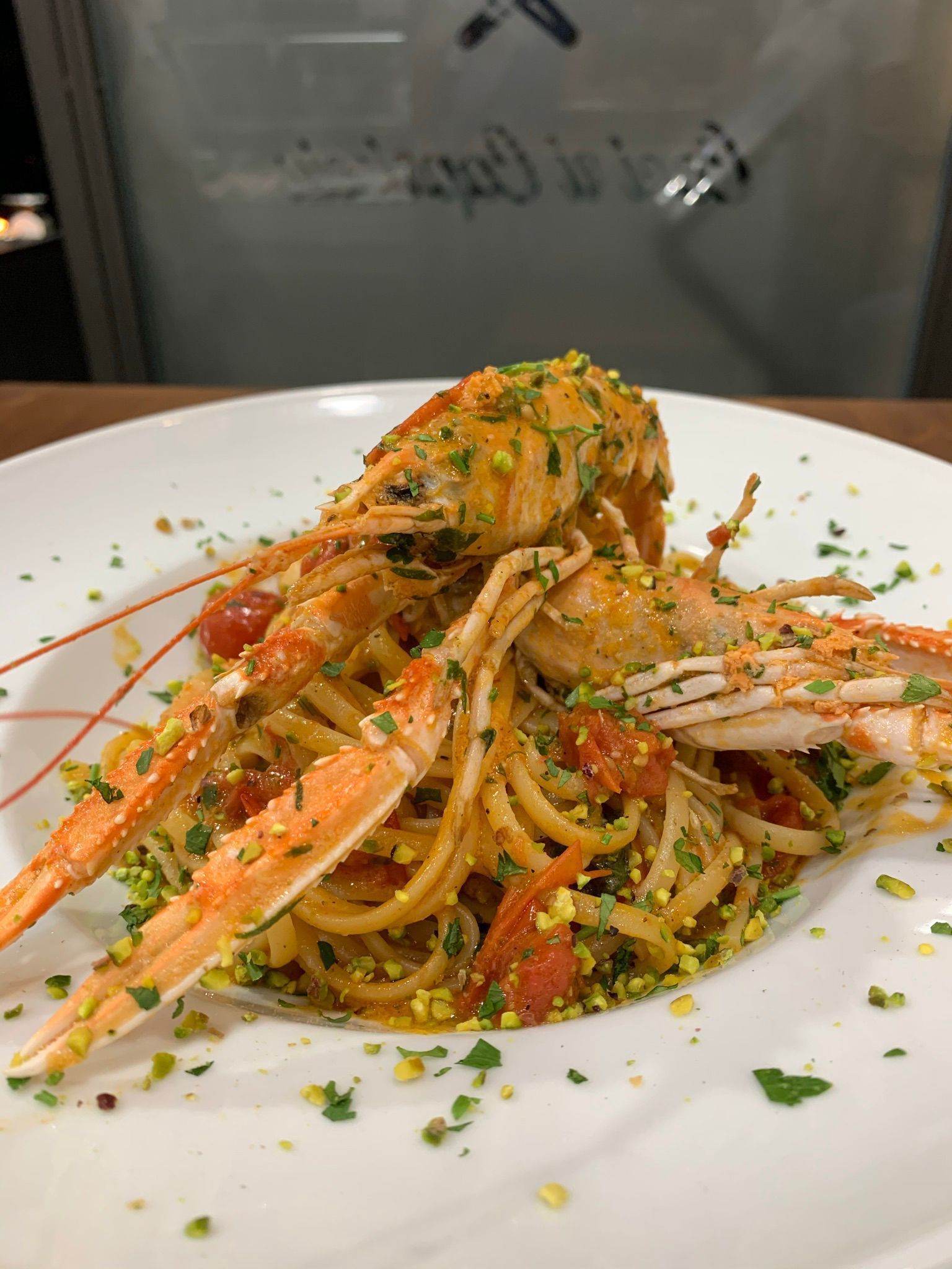 Un piatto bianco con sopra spaghetti e gamberi su un tavolo.