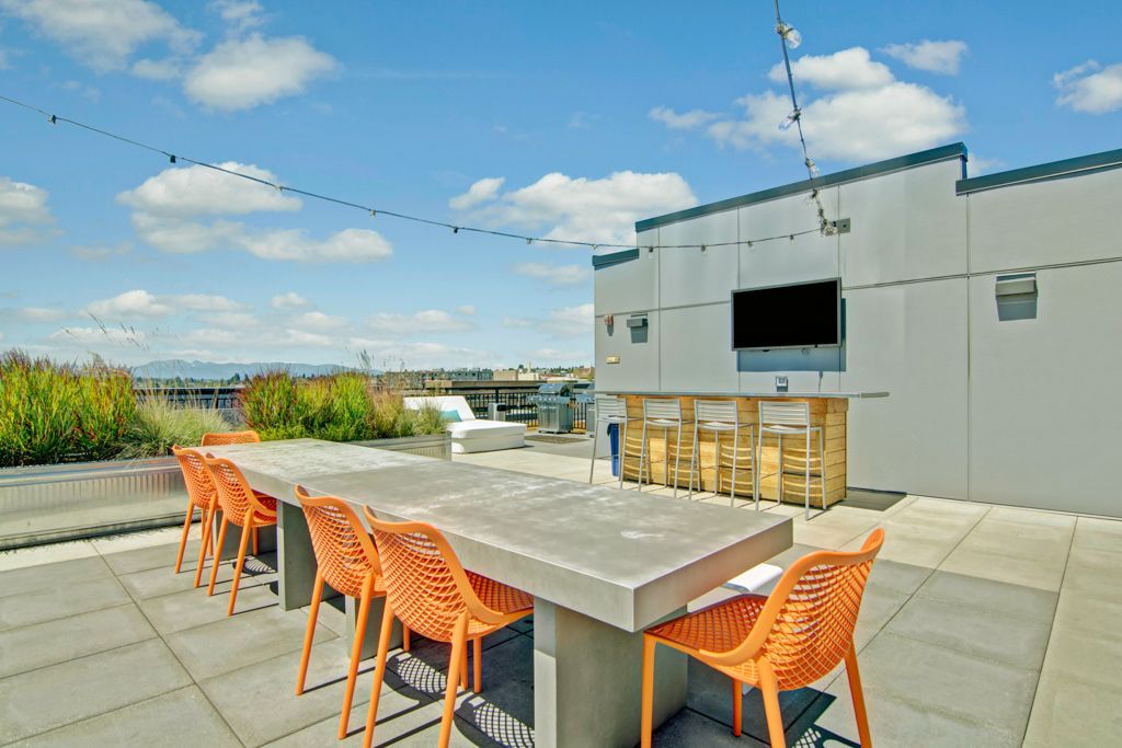 A patio with a long table and chairs on a sunny day.